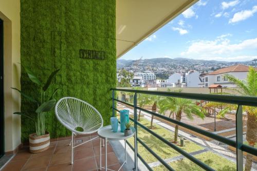 a balcony with a green wall and a table and chair at Vintage in Funchal