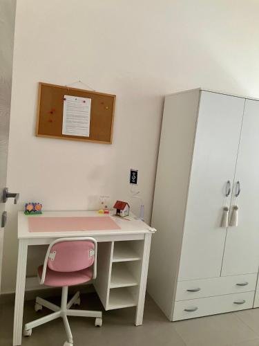 a desk with a pink chair and a cabinet at Casa Ulivo in San Sperate