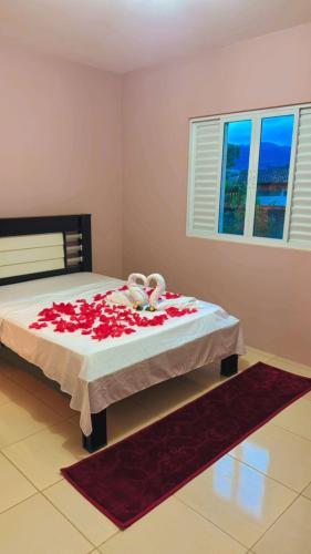 a bedroom with a bed with red flowers on it at Hospedagem Vô João in Gravatal