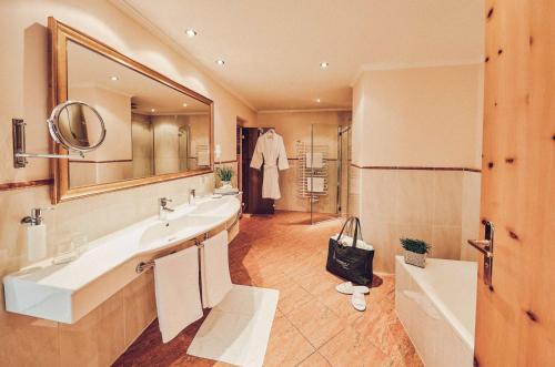 a bathroom with two sinks and a large mirror at Superior Sport und Familienresort Alpenblick in Zell am See
