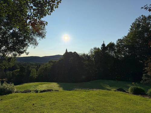 a view of a golf course with the sun in the sky at Auberge Matha in Saint-Jean-de-Matha
