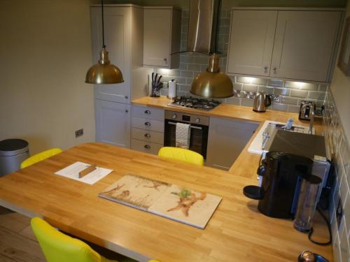 a kitchen with a wooden table with yellow chairs at Highlands - Speyside Suite in Skye of Curr