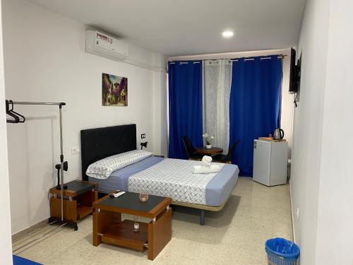 ein Schlafzimmer mit einem Bett mit blauen Vorhängen und einem Tisch in der Unterkunft costablanca rooms in Alicante