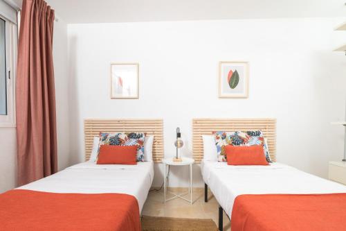 two beds in a room with red and white at Profithome- Brisas de Güimar in Puertito de Güímar
