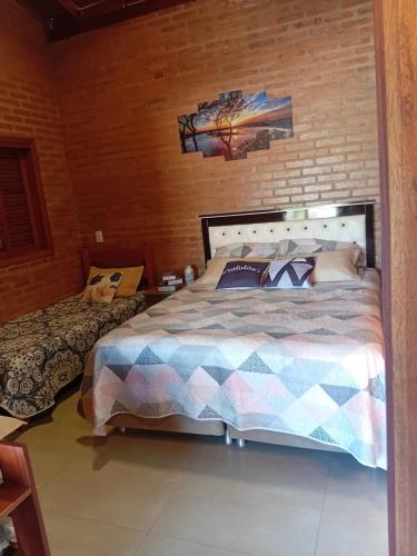 a bedroom with a bed and a brick wall at Vinhedos da Serra com Ar quente e frio até 5 pessoas in Espirito Santo Do Pinhal