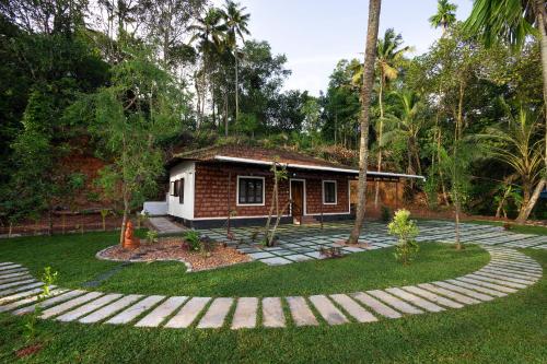 a small house with a garden in front of it at Anoop's Lake View Cottage -2BHK in Munroe Island
