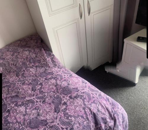 a bed with a purple comforter in a bedroom at E House in Great Gaddesden