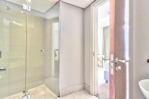 a bathroom with a glass shower and a sink at Cozy Apartment, WiFi, Centrally Located in Cape Town