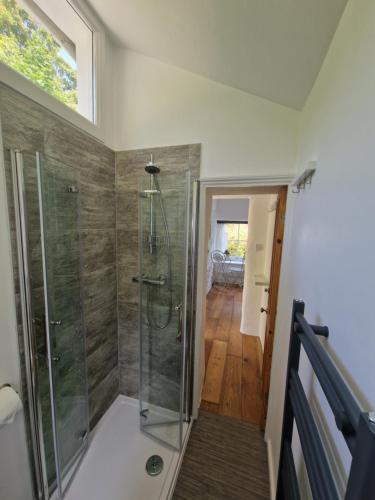 a bathroom with a shower with a glass shower stall at Primrose Cottage peaceful room and private garden in Helston