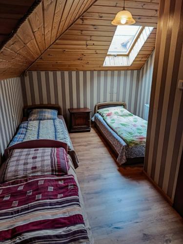 two beds in a room with a window at Willa Mortęgi in Lubawa