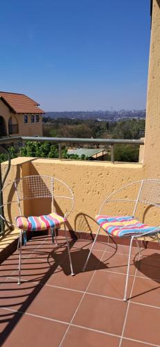 a patio with two chairs and a table at Bandile's cosy home in Honeydew