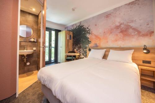 a bedroom with a white bed and a painting on the wall at Fletcher Hotel-Restaurant De Kempen in Reusel