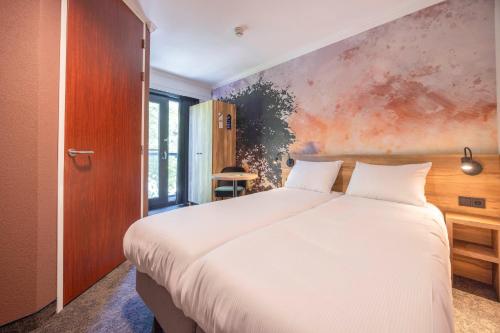 a bedroom with a white bed and a painting on the wall at Fletcher Hotel-Restaurant De Kempen in Reusel