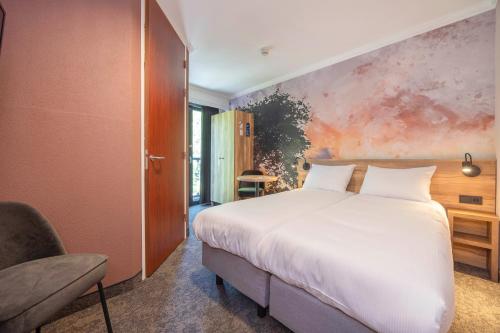 a bedroom with a large white bed and a chair at Fletcher Hotel-Restaurant De Kempen in Reusel