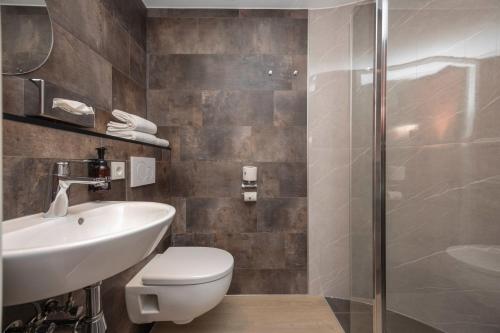 a bathroom with a toilet and a sink and a shower at Fletcher Hotel-Restaurant De Kempen in Reusel