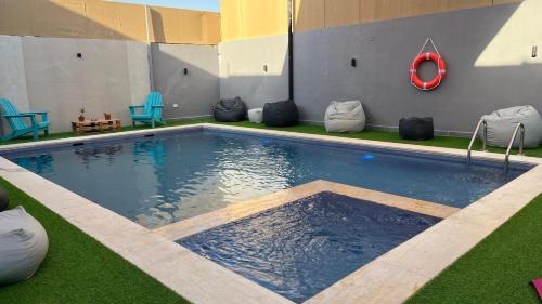 a large swimming pool with chairs on the grass at T Cozy Chalet in Ash Shāghūr