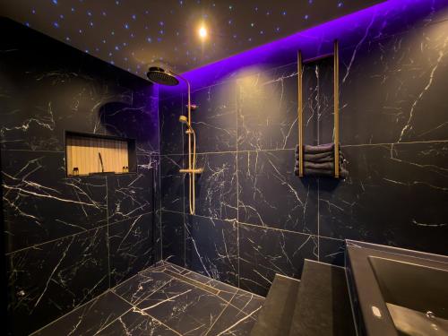 a bathroom with black marble walls and purple lighting at Royal Suite in 's-Gravenzande