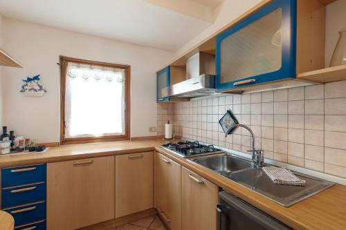 a kitchen with wooden cabinets and a sink and a window at Dolomitihouse AUNER in Fiera di Primiero