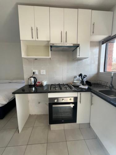 a kitchen with white cabinets and a stove top oven at The studios at Forest Glen in Johannesburg