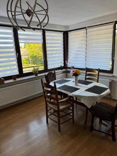 a dining room with a table and chairs and windows at MonteurGut Apartments Eiche in Lindern