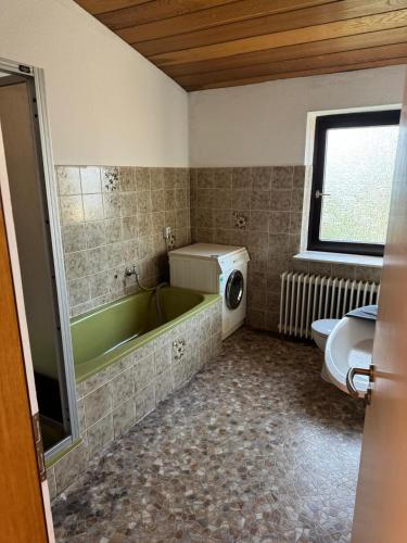 a bathroom with a green tub and a washing machine at MonteurGut Apartments Eiche in Lindern