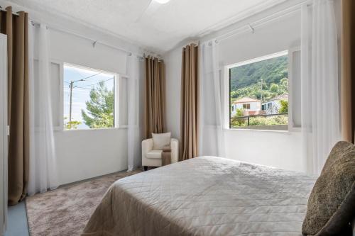 a bedroom with a bed and two windows at SUPER Zen in Ponta Delgada