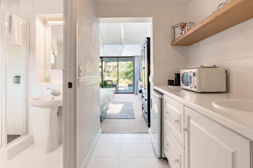 a white kitchen with a sink and a microwave at Bitou River Lodge in Plettenberg Bay