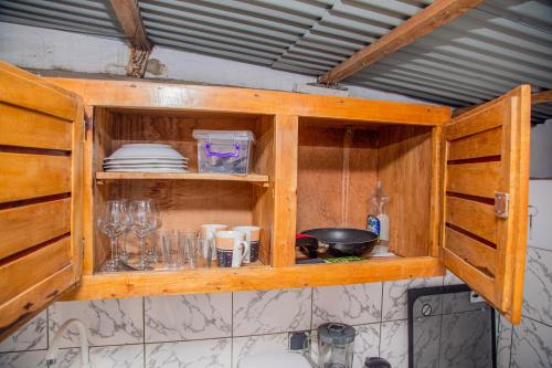 a kitchen with wooden cabinets with plates and dishes at Appartement 2 chambres 1 salon à 15mn aéroport plage in Cotonou