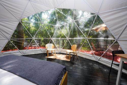 Una habitación con una cama y dos sillas en una tienda de campaña tipo domo. en Indómito Domes at El Yunque Zone, en Jayuya