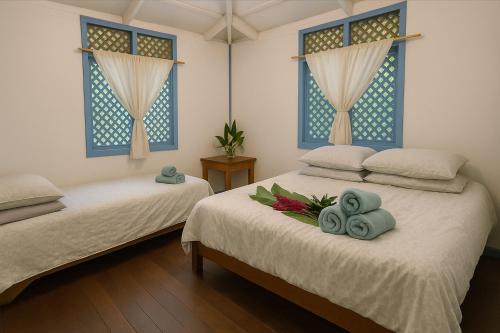 two beds in a room with blue windows at Villas Itaita Beach Cabins in Punta Uva