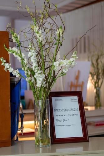 a vase filled with white flowers next to a framed picture at Garden Plaza Saigon - Formerly PARKROYAL Saigon in Ho Chi Minh City
