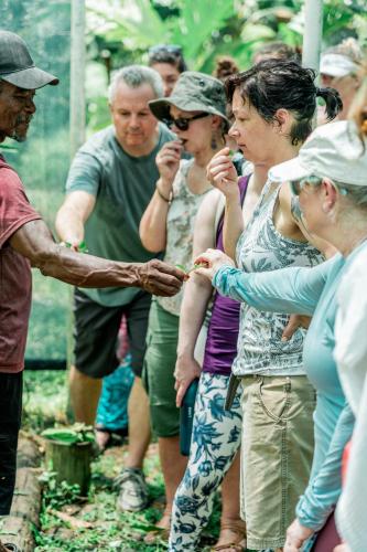 a group of people standing around a man holding a hand at La Loma Jungle Lodge and Chocolate Farm in Bocas del Toro