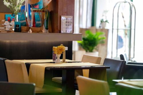 a table with chairs and a vase of flowers on it at Garden Plaza Saigon - Formerly PARKROYAL Saigon in Ho Chi Minh City