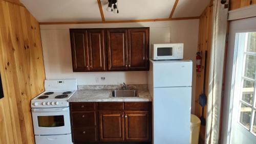 a kitchen with a white stove and a refrigerator at Millstream Cottages in Brackley Beach