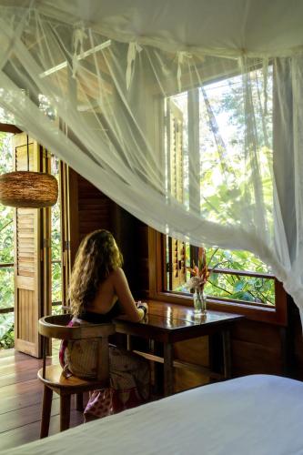 a woman sitting at a table in a bedroom at La Loma Jungle Lodge and Chocolate Farm in Bocas del Toro