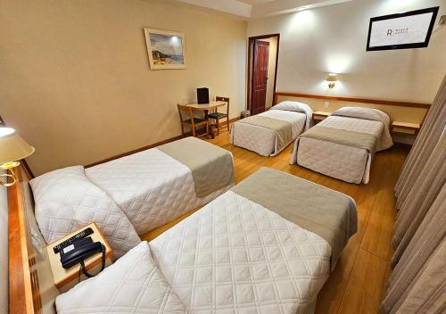 a hotel room with three beds and a table at Riale Imperial Flamengo in Rio de Janeiro