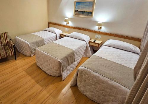 three beds in a hotel room with wood floors at Riale Imperial Flamengo in Rio de Janeiro