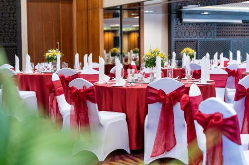 a set of tables with red and white tablecloths and bows at Garden Plaza Saigon - Formerly PARKROYAL Saigon in Ho Chi Minh City