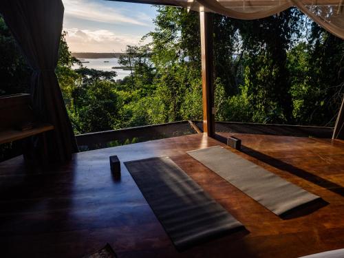 a room with a table with a view of the water at La Loma Jungle Lodge and Chocolate Farm in Bocas del Toro