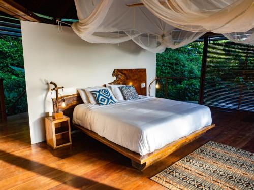 a bedroom with a bed and a large window at La Loma Jungle Lodge and Chocolate Farm in Bocas del Toro