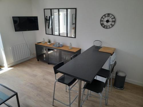 une salle à manger avec une table, des chaises et une horloge dans l'établissement Location vacances kerroch, à Ploemeur