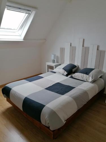 un grand lit dans une chambre blanche avec une fenêtre dans l'établissement Location vacances kerroch, à Ploemeur