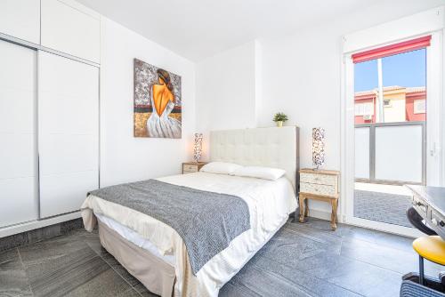 a white bedroom with a bed and a window at VillasRoyale Trespalomas - An Iconic Villa for Elevated Getaways! in Meloneras