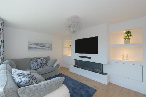 a living room with a couch and a tv on a wall at MODERN 3 BEDROOM PROPERTY WITH FREE DRIVEWAY PARKING by SHIRE STAYS in Shrewsbury