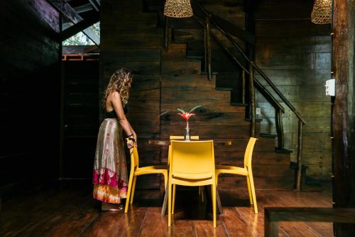 a woman standing next to a table and two chairs at La Loma Jungle Lodge and Chocolate Farm in Bocas del Toro