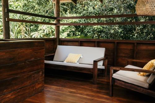 a porch with a white bench and a table at La Loma Jungle Lodge and Chocolate Farm in Bocas del Toro