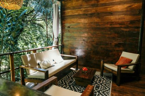 a porch with two chairs and a table and a table at La Loma Jungle Lodge and Chocolate Farm in Bocas del Toro