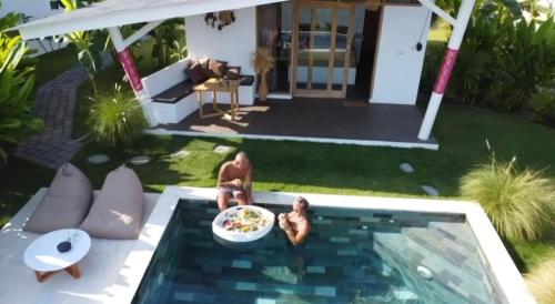 deux personnes dans une piscine avec un bol de nourriture dans l'établissement EDEN Eco-Villas with Private Pool and Panoramic Sea View - ADULT ONLY, à Nusa Penida
