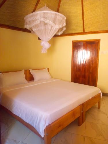 a bedroom with a white bed with a chandelier at New Court View Hotel in Masindi