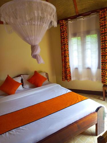 a bedroom with a bed with orange pillows and a window at New Court View Hotel in Masindi